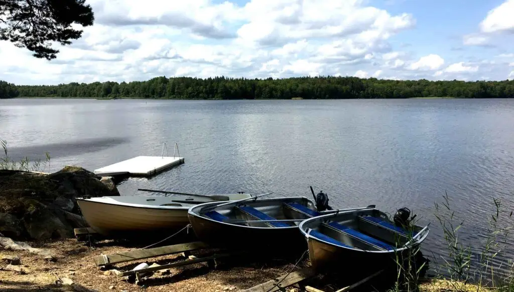 Linder aluminiumbåtar vid egen brygga i Åsnens Nationalpark, perfekt för fiske, bad och avkoppling vid sjön.