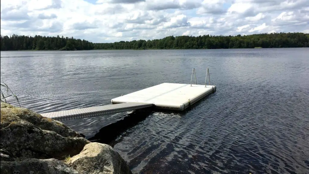 Egen brygga vid sjö i Åsnens Nationalpark med badstege, lugnt vatten och naturnära omgivning i Småland.