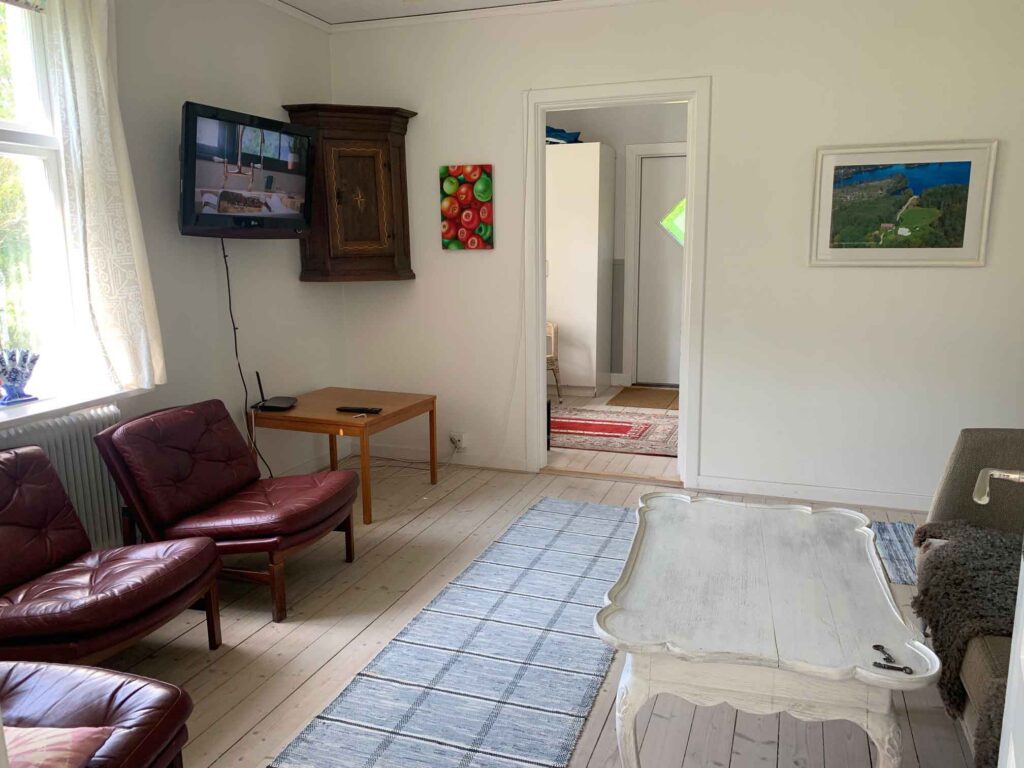 Vardagsrum med bekväma fåtöljer, soffa, soffbord och väggmonterad TV i ljus och hemtrevlig miljö.