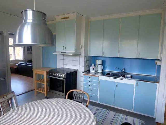 Kök på andra våningen med ljusblå skåpsluckor, full utrustning och matplats i rymligt hus anpassat för två familjer.